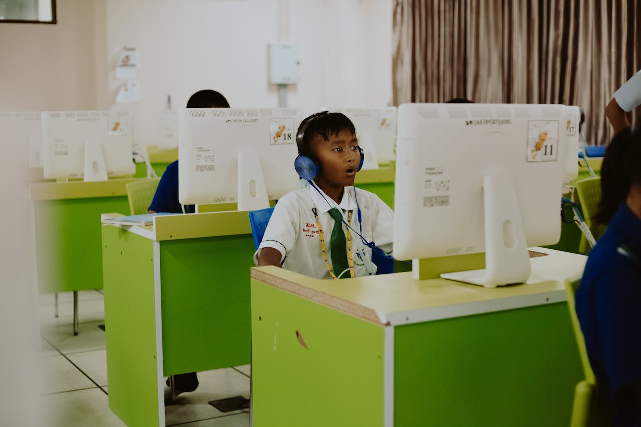 A child in a school computer lab focused on learning with headphones on.